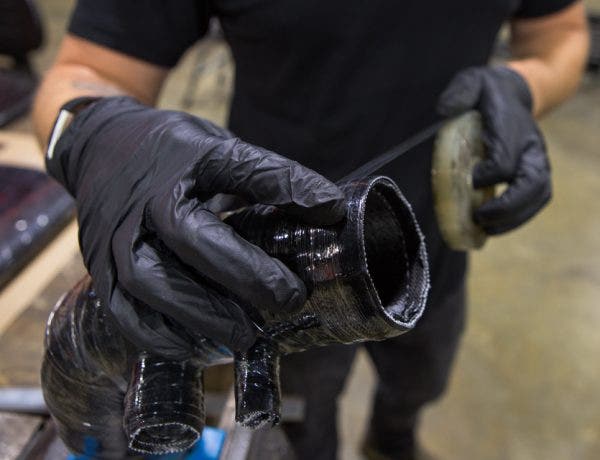 Before the hose gets cured in the oven, Mike wraps it using a binding tape. This tape makes sure the hose holds its shape around the mold while it cures. The tape is removed after the curing process, which gives the final product that tightly bound texture.