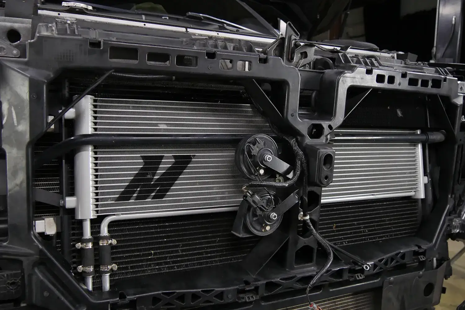 An image of a Ford F250 Super-Duty with the grille removed and a Mishimoto transmission cooler installed in front of the radiator.