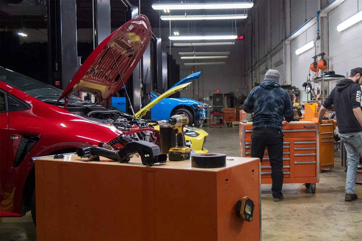 An image of Mishimoto engineers test-fitting a radiator prototype on a red 2023 Toyota GR Corolla.